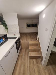 een keuken met witte kasten, houten vloeren en een trap bij Cohens apartments in Jeruzalem