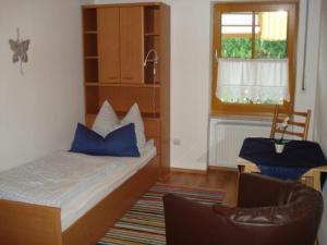 um quarto com uma cama, uma cadeira e uma janela em Ferienwohnungen Schellein em Blaibach