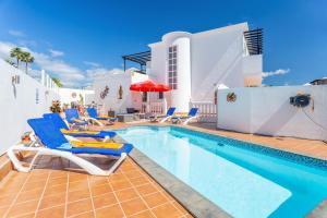 a swimming pool with lounge chairs and a house at Casa Laura in Puerto del Carmen