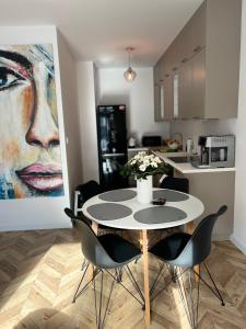 una mesa y sillas en una cocina con una pintura en Uroczy apartament z ogrodem, en Rumia