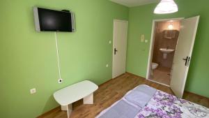 a green room with a bed and a tv on the wall at J&Z Rooms in Burgas