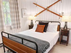 a bedroom with a bed with two lamps and two tables at Stylish and Cozy Cabin, Walking Distance to Big Bass Lake in Gouldsboro