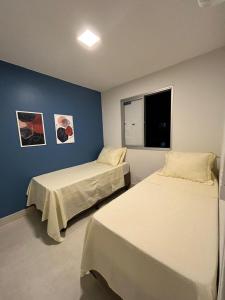 a bedroom with two beds and a blue wall at Lindo apartamento no Setor Bueno- todo reformado - tudo novinho -Sua busca termina aqui in Goiânia