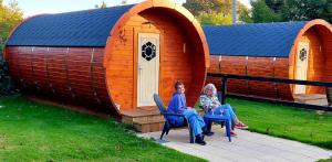zwei Frauen auf Stühlen vor einem Spielhaus in der Unterkunft Glamping at Treegrove in Kilkenny