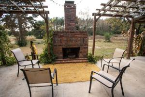 a patio with chairs and a brick fireplace at Nebo's Foot, Cabin Escape with Game-Barn in Dardanelle