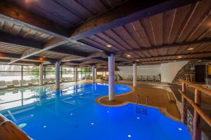a large swimming pool with blue water in a building at Hotel Slovan in Tatranská Lomnica