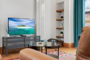 una sala de estar con un televisor y una mesa en The Old Cooperage by Staytor Accommodation, en Exeter