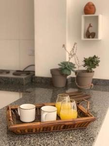 una bandeja de zumo de naranja y tazas en la encimera de la cocina en Oko Apartment en Salta