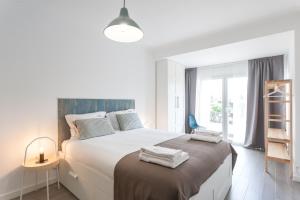 biała sypialnia z dużym łóżkiem i ręcznikami w obiekcie Grand Beach House Bliss, By TimeCooler w mieście Carcavelos