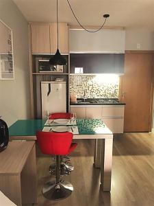 een keuken met een tafel en een rode stoel bij Studio Moderno e Aconchegante in Curitiba