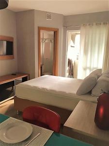 a bedroom with a large white bed and a table at Studio Moderno e Aconchegante in Curitiba