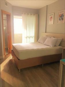 1 cama grande en un dormitorio con ventana en Studio Moderno e Aconchegante en Curitiba