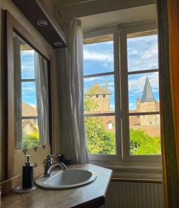 lavabo en el baño y ventana con vistas al castillo en Maison Sainte Barbe, en Autun