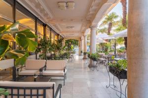 a restaurant with tables and chairs and palm trees at Hotel Bellevue - Liburnia in Opatija