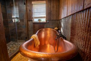 uma grande banheira de cobre na casa de banho com chuveiro em Nebo's Foot, Cabin Escape with Game-Barn em Dardanelle
