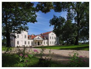 a large white house with trees and flowers at Pałac Łochów in Łochów