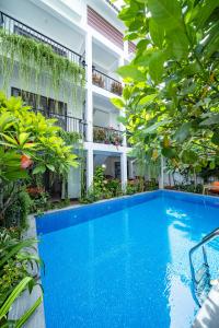 a swimming pool in front of a building with trees at My Anh Boutique Villa Hoi An in Hoi An