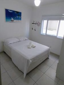 a white bedroom with a bed and a window at Espaçoso aconchegante in Capão da Canoa
