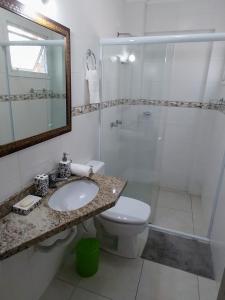 uma casa de banho com um WC, um chuveiro e um lavatório. em Espaçoso aconchegante em Capão da Canoa