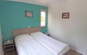 a white bed in a room with a blue wall at Strandbungalow Jette in Glowe +1 photo