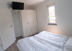 a white bedroom with a bed and a window at Strandbungalow Jette in Glowe