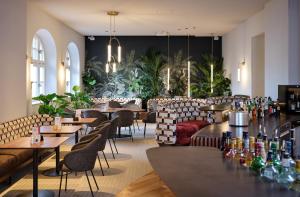 un restaurante con mesas, sillas y plantas en Asam Hotel, en Straubing