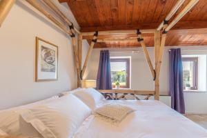 sypialnia z białym łóżkiem i drewnianym sufitem w obiekcie DOLF - Porta Gemina w mieście Urbisaglia