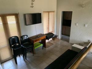 salon z biurkiem, krzesłami i telewizorem w obiekcie Mabalingwe Elephant Lodge 256A w mieście Moheme