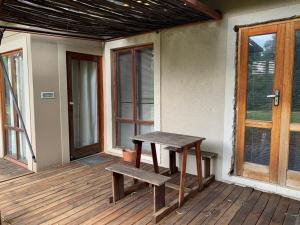 un banco de madera sentado en el porche de una casa en Mabalingwe Elephant Lodge 256A, en Moheme