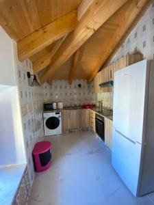 a kitchen with a white refrigerator and wooden ceilings at La carchata ático in Siete Aguas