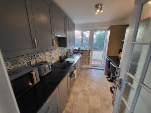 a kitchen with black counter tops and a large window at Modern 3 bed Walking Distance to Wimbledon Tennis! in London