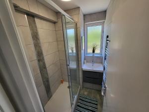 Modern 3 bed Walking Distance to Wimbledon Tennis! في لندن: حمام مع دش ومغسلة ونافذة