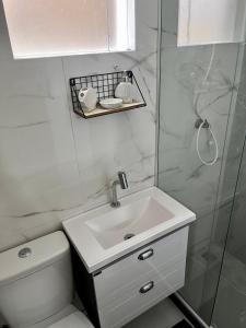 a white bathroom with a sink and a shower at Meu Loft Geribá em Búzios in Búzios