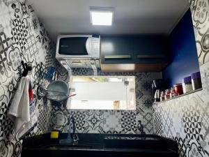 eine kleine Küche mit einer Spüle und einer Mikrowelle in der Unterkunft Meu Loft Geribá em Búzios in Búzios