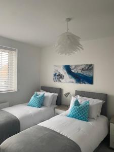 a bedroom with two beds with blue pillows at Henry Blythe Gardens in Thame