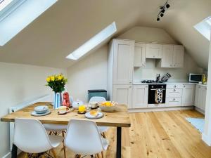 a kitchen with a wooden table and white chairs at Vindelis Cottage Chesil Beach in Portland