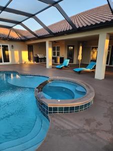 een groot zwembad met blauwe stoelen en een huis bij Luxury Spanish-style vacation home! 