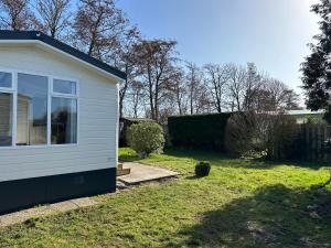 een klein wit huis met een tuin met gras bij Chalet 550 op Recreatiepark de Wielen in Sint Maarten