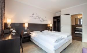 Schlafzimmer mit einem großen weißen Bett und einem Schreibtisch in der Unterkunft Hotel Banter Hof in Wilhelmshaven