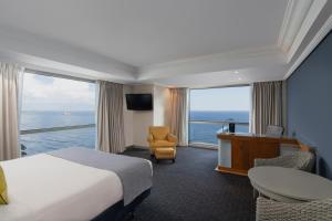 um quarto de hotel com uma cama, uma secretária e janelas em Catalonia Santo Domingo em Santo Domingo