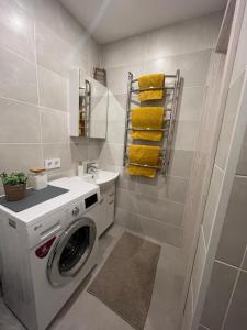 ein Badezimmer mit einer Waschmaschine und einem Waschbecken in der Unterkunft ESSE Apartament in Gulbene