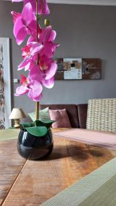 um vaso com flores cor-de-rosa numa mesa de madeira em STUDIOS ET APPARTEMENTS EN CENTRE VILLE Boulogne sur mer em Boulogne-sur-Mer