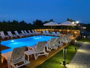 a group of chairs and a swimming pool at night at Mikołajek in Jarosławiec