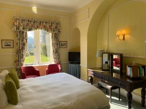 a bedroom with a bed and a desk and a window at Langrish House in Petersfield