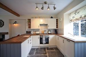 a kitchen with white cabinets and a counter top at 1 Kirkbeck Cottage Coniston in Coniston +6 photos