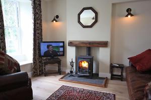 a living room with a fireplace and a tv at 1 Kirkbeck Cottage Coniston in Coniston