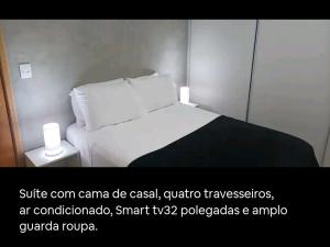 a bed with white sheets and pillows in a room at Apartamento Sol Poente in Ribeirão Preto