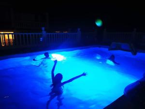 two children playing in a swimming pool at night at Villa Paraiso - Appartement 2 pièces privatif in Alhaurín de la Torre