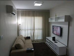 a living room with a couch and a flat screen tv at Apartamento Sol Poente in Ribeirão Preto