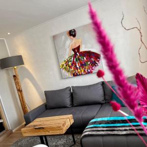 a living room with a couch and a painting of a woman at Die Altstadt Appartements Caprice in Goslar